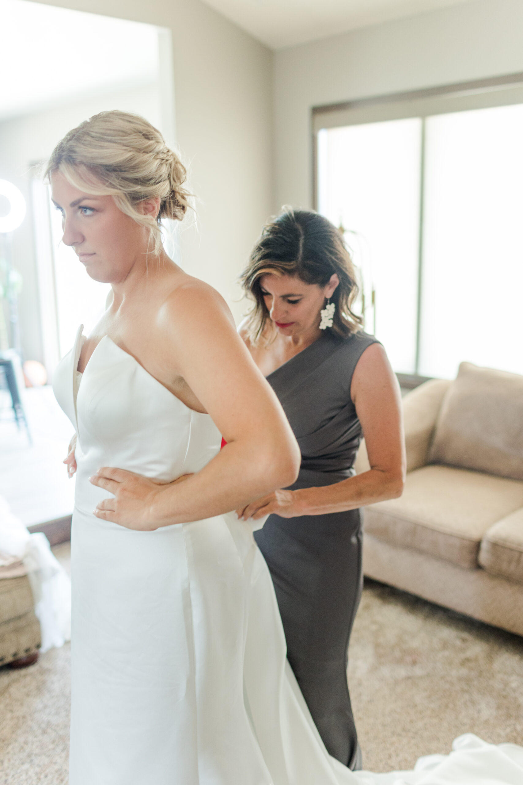 Bridal shop owner helping Bride into wedding dress